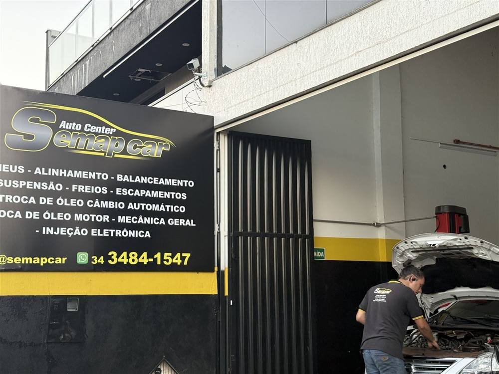 Mecânico da Semap Car conferindo o motor de um carro na oficina, com o letreiro da loja ao fundo